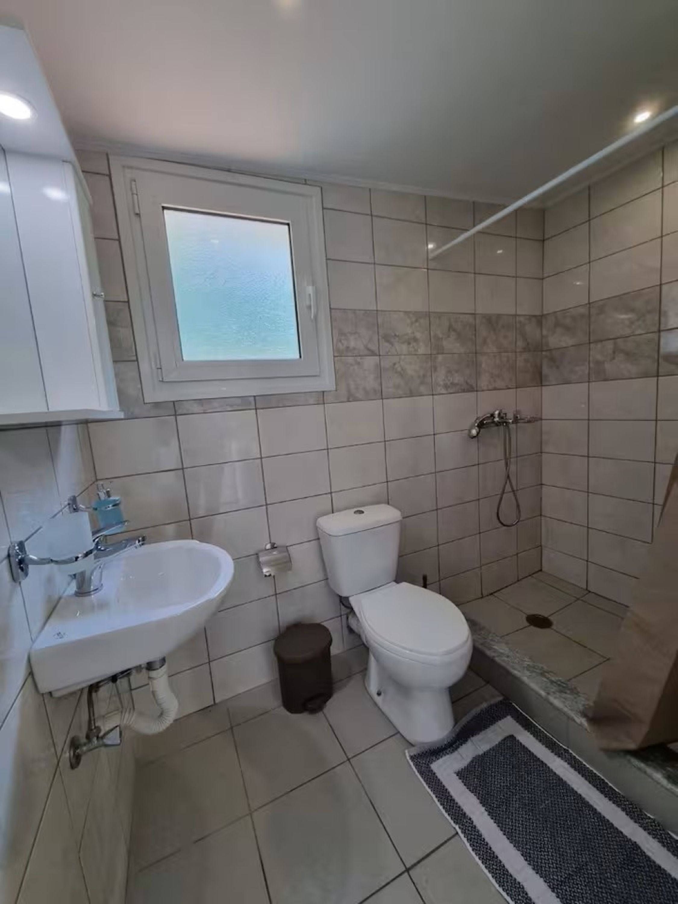 A bathroom with a toilet, sink, and shower.