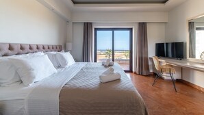 A hotel room with a large bed, a desk with a chair, a television, and a balcony with a view of the beach. - Bliss Villa 3 with private swimming pool (Anissaras)