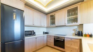 A modern kitchen with light wood cabinets, a stainless steel refrigerator, a microwave, a dishwasher, and a glass-fronted cabinet with glassware. - Bliss Villa 3 with private swimming pool (Anissaras)