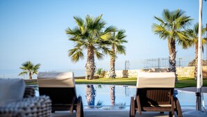 A poolside area with lounge chairs and palm trees. - Bliss Villa 3 with private swimming pool (Anissaras)