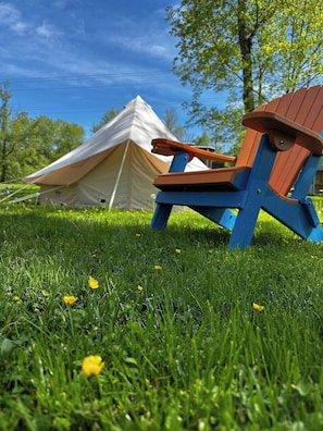 A tent and a wooden chair in a grassy field.