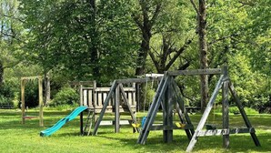 A playground with swings and a slide in a grassy park area.