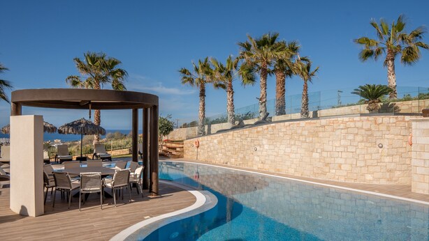 Ein Poolbereich mit Holzterrasse, Liegestühlen und einer Pergola.
