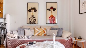 A modern living room with a sofa, a small round table, and a white fluffy rug. There are two framed artworks above the sofa. - Cozy in Athens Neos Kosmos, an original vibe (Athina)