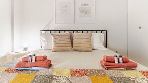 A neatly made bed with striped pillows, a quilt, and towels on the bed. - Cozy in Athens Neos Kosmos, an original vibe (Athina)