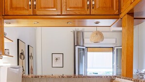 A kitchen with wooden cabinets, a white countertop, a sink, and a microwave. - Cozy in Athens Neos Kosmos, an original vibe (Athina)