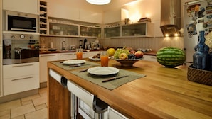Una cocina moderna con encimera de madera, electrodomésticos integrados y un frutero.