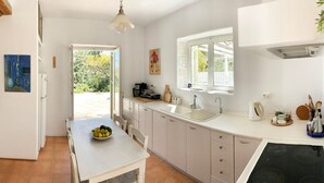 A kitchen with a dining area, a window with a view, and a sink. - Villa Joy in Ampelas, Paros (Ampelas)