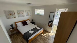Une chambre à coucher avec un lit en bois, une table de chevet, un miroir et des œuvres d’art accrochées au mur.