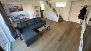 Un vaste espace de vie comprenant un canapé gris, une petite table basse et un escalier menant à un autre niveau.
