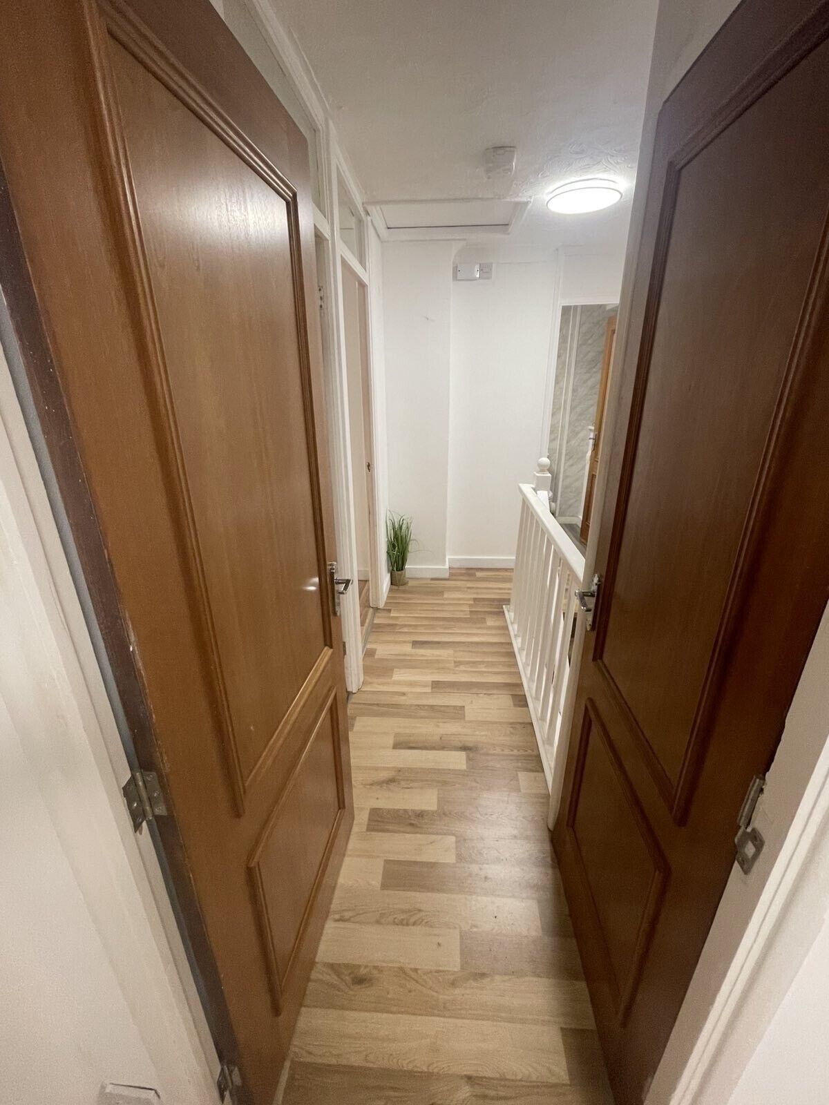 A narrow hallway with wooden doors and a herringbone-patterned floor.