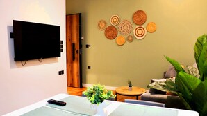 Un soggiorno moderno con una TV a schermo piatto montata a parete, un tavolino rotondo e un angolo relax con un divano.