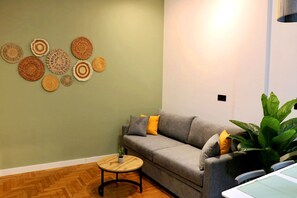 Ein Wohnzimmer mit grauem Sofa, einem runden Holztisch und einer Wand, die mit runden gewebten Kunstwerken verziert ist.