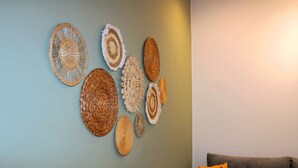 Una parete decorata con diversi arazzi e un divano con un cuscino arancione.