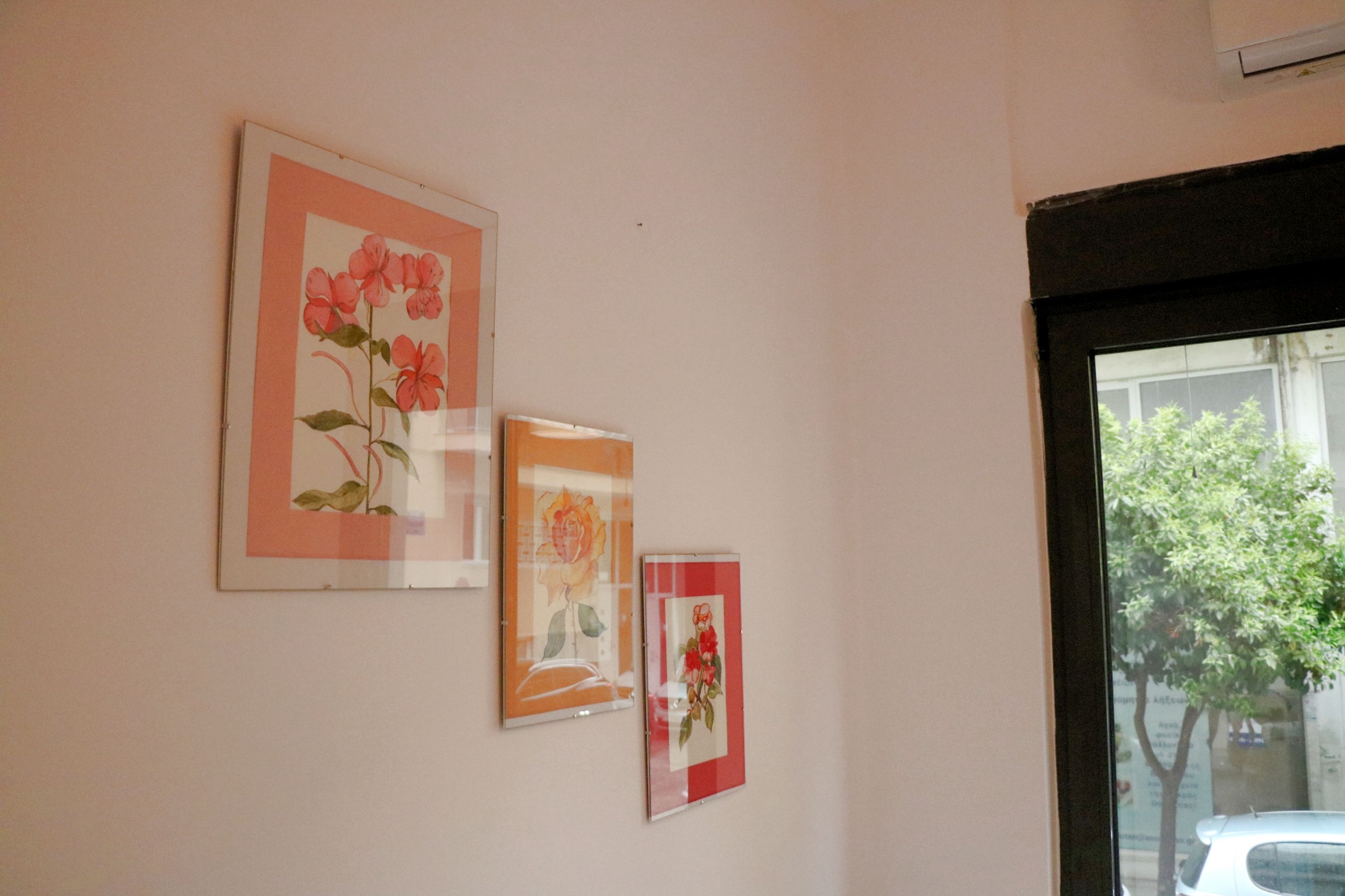 A wall with three framed floral artworks.