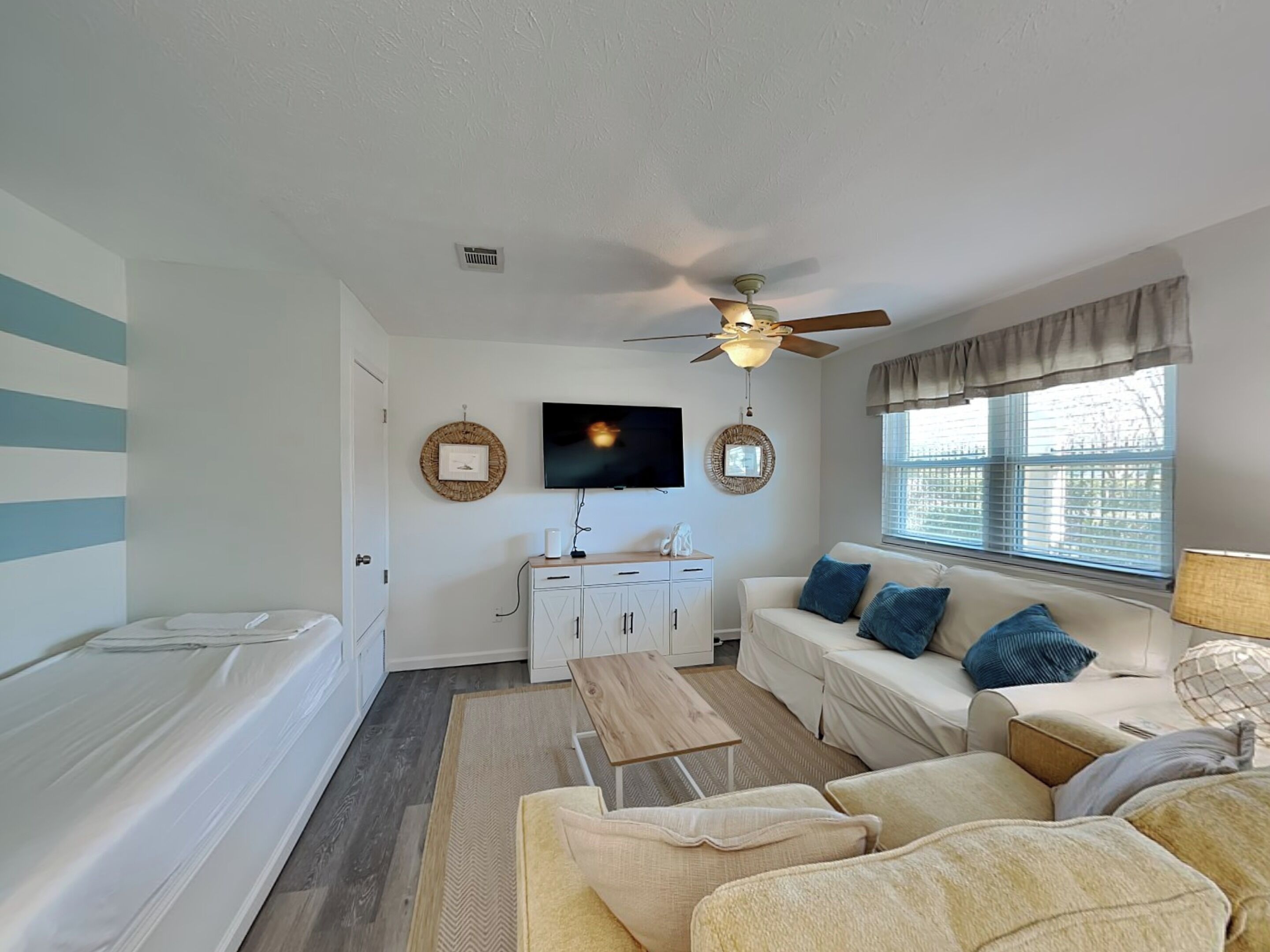 A modern living room with a sofa, a coffee table, a TV, and a ceiling fan.