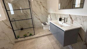 Een moderne badkamer met een douchecabine van glas, een toilet en een wastafel met spiegel erboven.