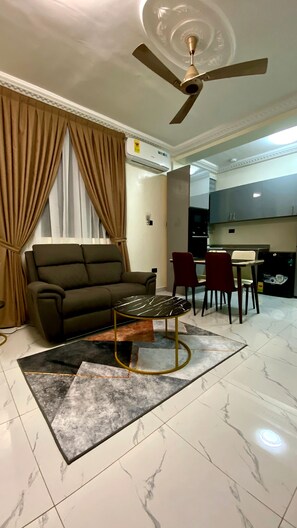 A living room with a sofa, a coffee table, and a ceiling fan. - Deluxe One Bed room Apartment, BH Apartments (Dansoman)
