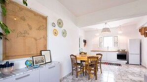 Eine kompakte Küche mit weißen Schränken, einem Esstisch mit Stühlen, einer großen Karte an der Wand und einem Kühlschrank.