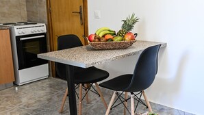 Una cucina con un piano di lavoro in granito, due sedie nere, una porta in legno e un piccolo tavolo rotondo con una pianta in vaso.