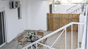 Una terrazza sul tetto con tavolo e sedie, una scala e vista sugli edifici circostanti.