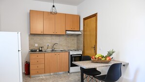 Una cucina compatta con mobili in legno, un fornello a gas, un lavello e un'area pranzo con tavolo e sedie.