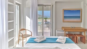 A hotel room with a bed, a chair, a desk, and a view of the beach. - Villa Helia with swimming pool (Naousa)