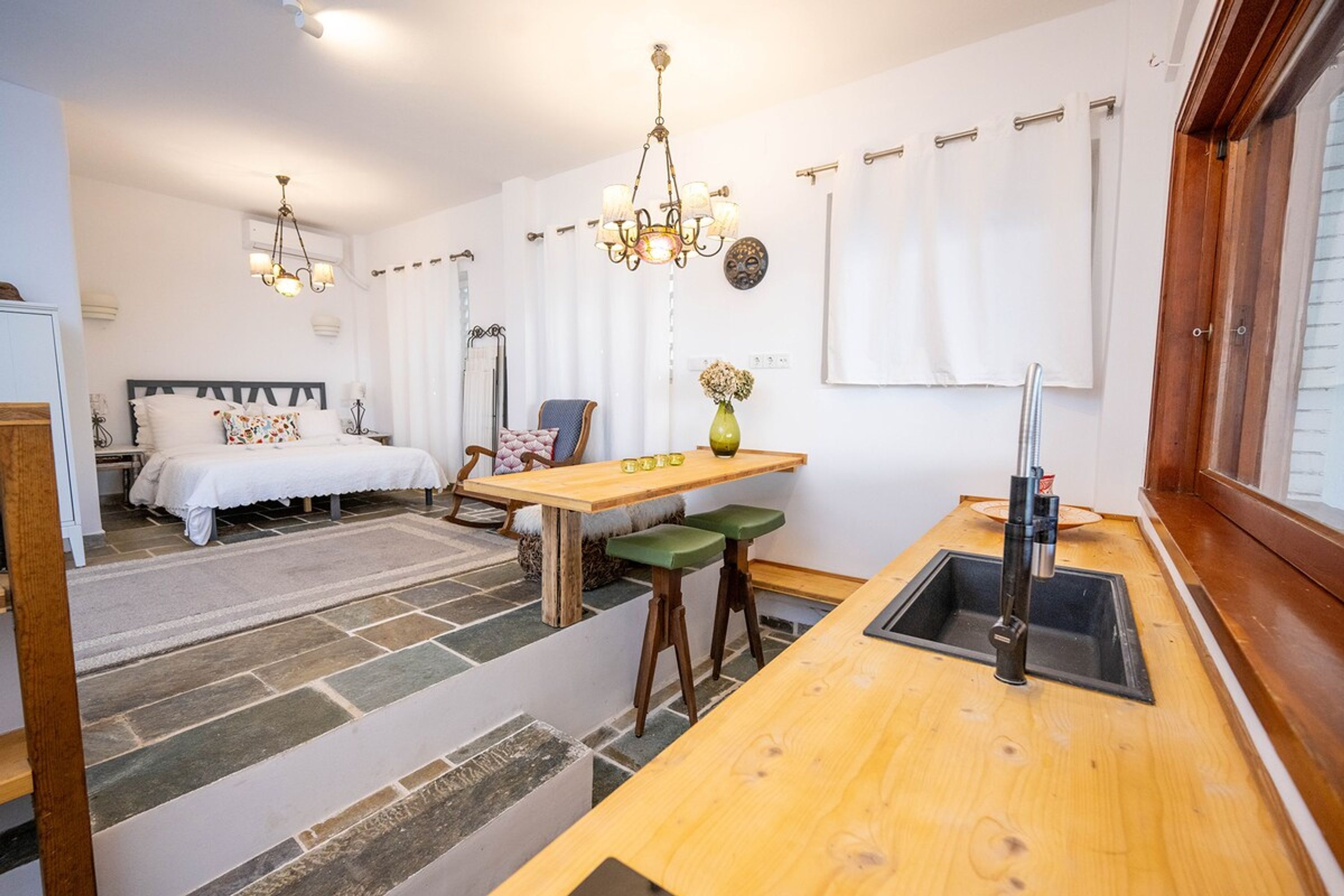 A compact kitchen with a wooden countertop, a sink, and a dining area with a table and chairs.