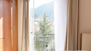 Une chambre à coucher avec un lit, une armoire en bois et une fenêtre avec des rideaux.