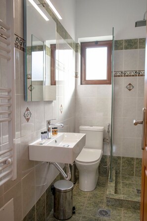 Une salle de bain avec un lavabo blanc, des toilettes et une douche à parois de verre.