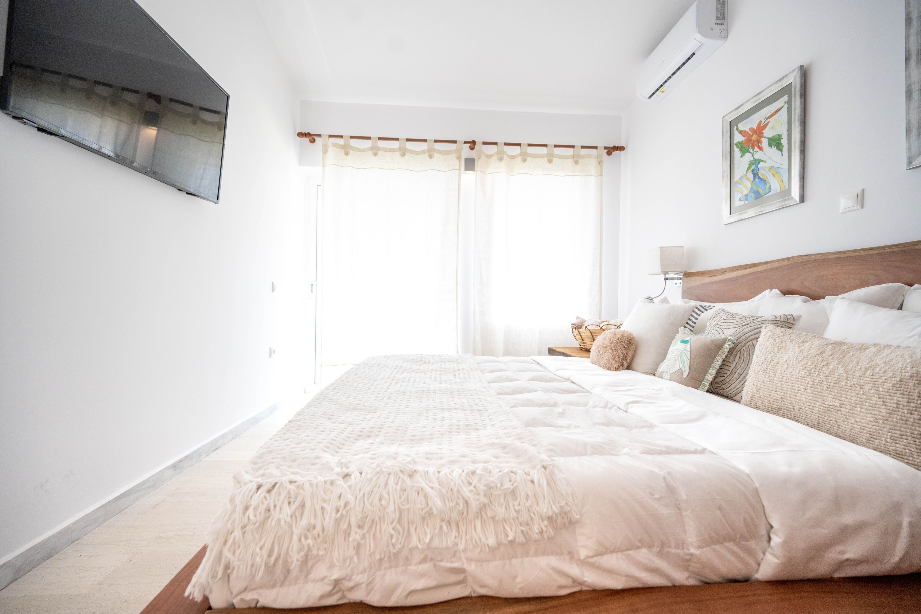 A bedroom with a large bed, a bedside table, a lamp, and a painting on the wall.