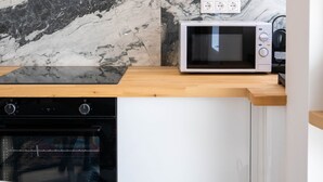 Una cucina compatta con forno a microonde integrato, forno e cappa in acciaio inossidabile.