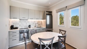 Una cocina moderna con una isla central, electrodomésticos integrados y un comedor con cuatro sillas.