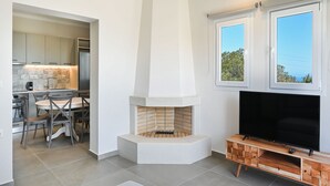 Une cuisine moderne dotée d’une cuisinière intégrée, d’un coin repas avec des chaises et d’un téléviseur posé sur un meuble en bois.