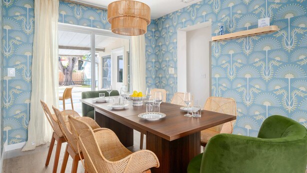 Un coin repas avec une table en bois, des chaises en osier et un luminaire suspendu.