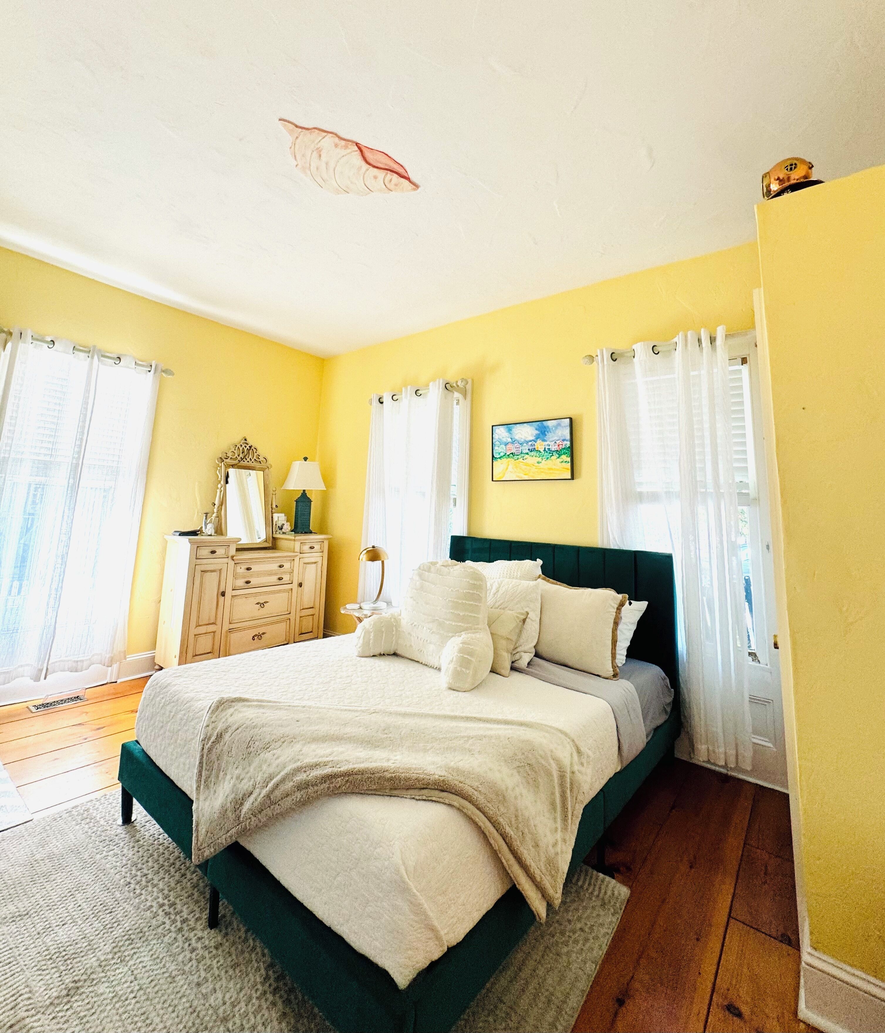 A bedroom with a bed, dresser, and a painting on the wall.
