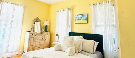 A bedroom with a bed, dresser, and a painting on the wall.