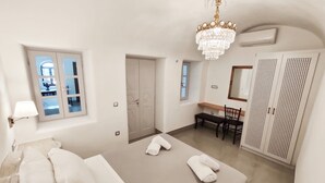 Ein Hotelzimmer mit einem großen Bett, einem Schreibtisch, einem Stuhl, einem Kleiderschrank und einer Chandelüster.