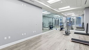 A modern gym with mirrored walls, exercise equipment, and a wooden floor. - King Studio with Partial Water Views, Heated Pool, Beach Access (Daytona Beach)