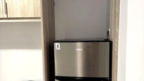 A compact kitchen with a stainless steel refrigerator, wooden cabinets, and a green chair. - Athenian Stay Chara's 2 Apartment (Neo Psichiko)