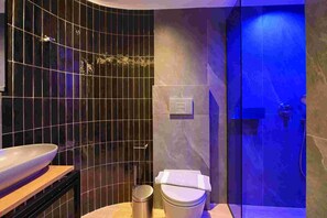 Une salle de bain moderne avec un mur incurvé, une douche en verre et un lavabo doté d’un plan de travail en marbre.