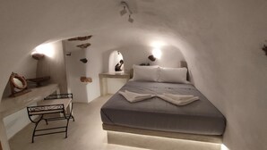 Ein gemütliches Schlafzimmer mit weißen Wänden, einem Bett, einem kleinen Schreibtisch und einem Stuhl.