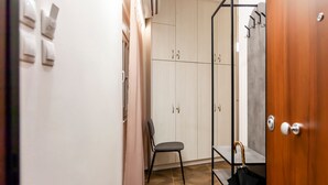 Un pasillo con una puerta de madera, una silla y un armario con varias puertas.