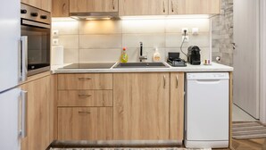 Una cocina moderna con armarios de madera, horno integrado, lavavajillas y una encimera con un lavabo y varios electrodomésticos.
