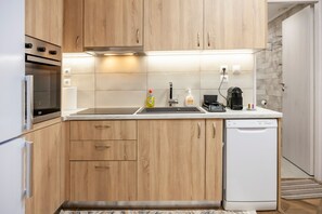 Une cuisine moderne avec des meubles en bois, un four encastré, un lave-vaisselle et un évier en acier inoxydable.