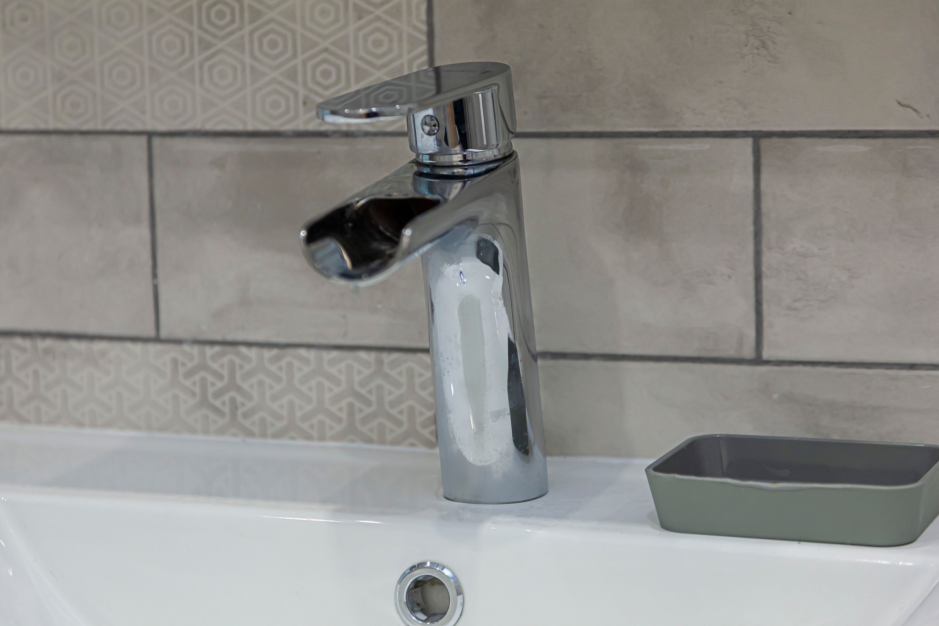Un lavabo de salle de bain avec un robinet chromé et un bac rectangulaire.