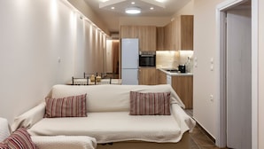 Una sala de estar moderna con un sofá, un comedor y una cocina con armarios de madera y un refrigerador.