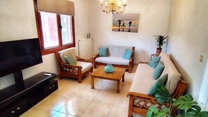 A living room with a sofa set, a coffee table, a TV, and a potted plant. - La Casa di Teta by superhosthub (Galatas)