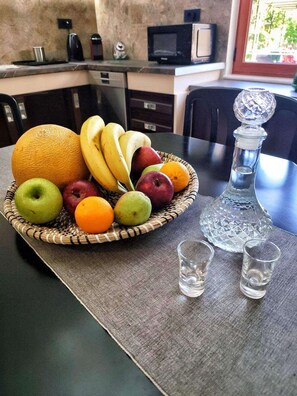 A dining table with a fruit basket, two shot glasses, and a crystal decanter. - La Casa di Teta by superhosthub (Galatas)
