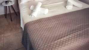 A neatly made bed with white linens and a brown quilted bedspread, two bedside tables with lamps, and a tiled floor. - La Casa di Teta by superhosthub (Galatas)